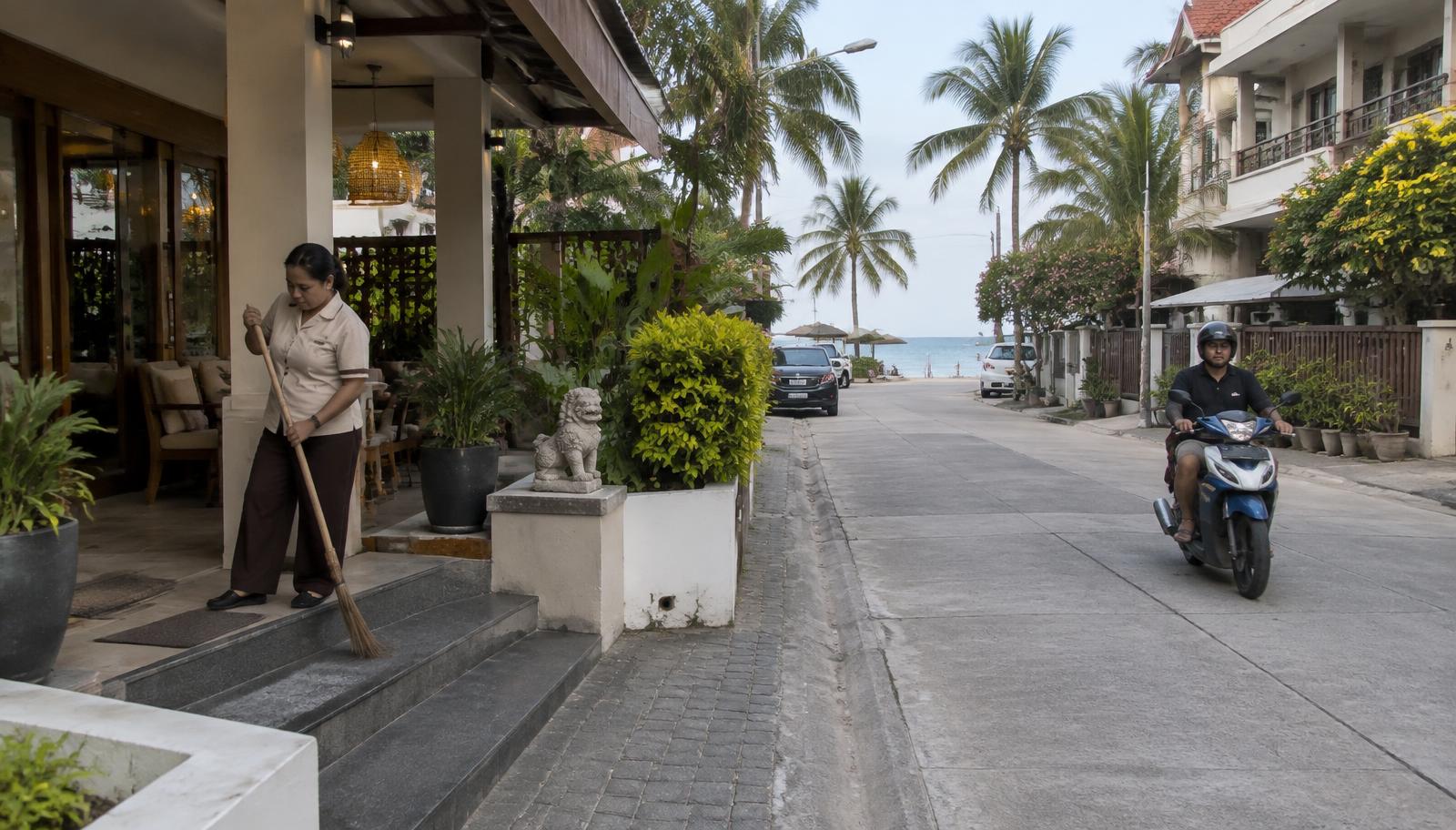 ถนนเลียบชายหาดในหัวหิน จังหวัดประจวบคีรีขันธ์ มีที่พักขนาดเล็กและพนักงานกวาดทางเข้า
