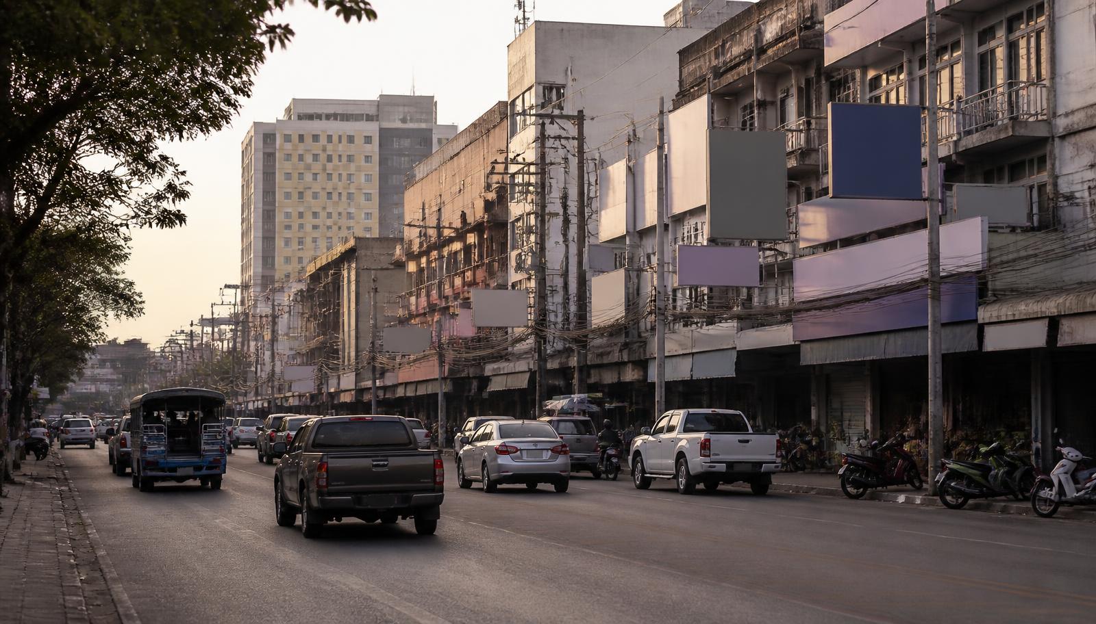 ถนนสายหลักในเมืองอุดรธานีช่วงเย็น มีอาคารพาณิชย์ โรงแรม รถสองแถวและรถกระบะวิ่งผ่าน